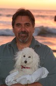 Mark holding his poodle friend, Tessie, at a sunset beach in Cambria, California